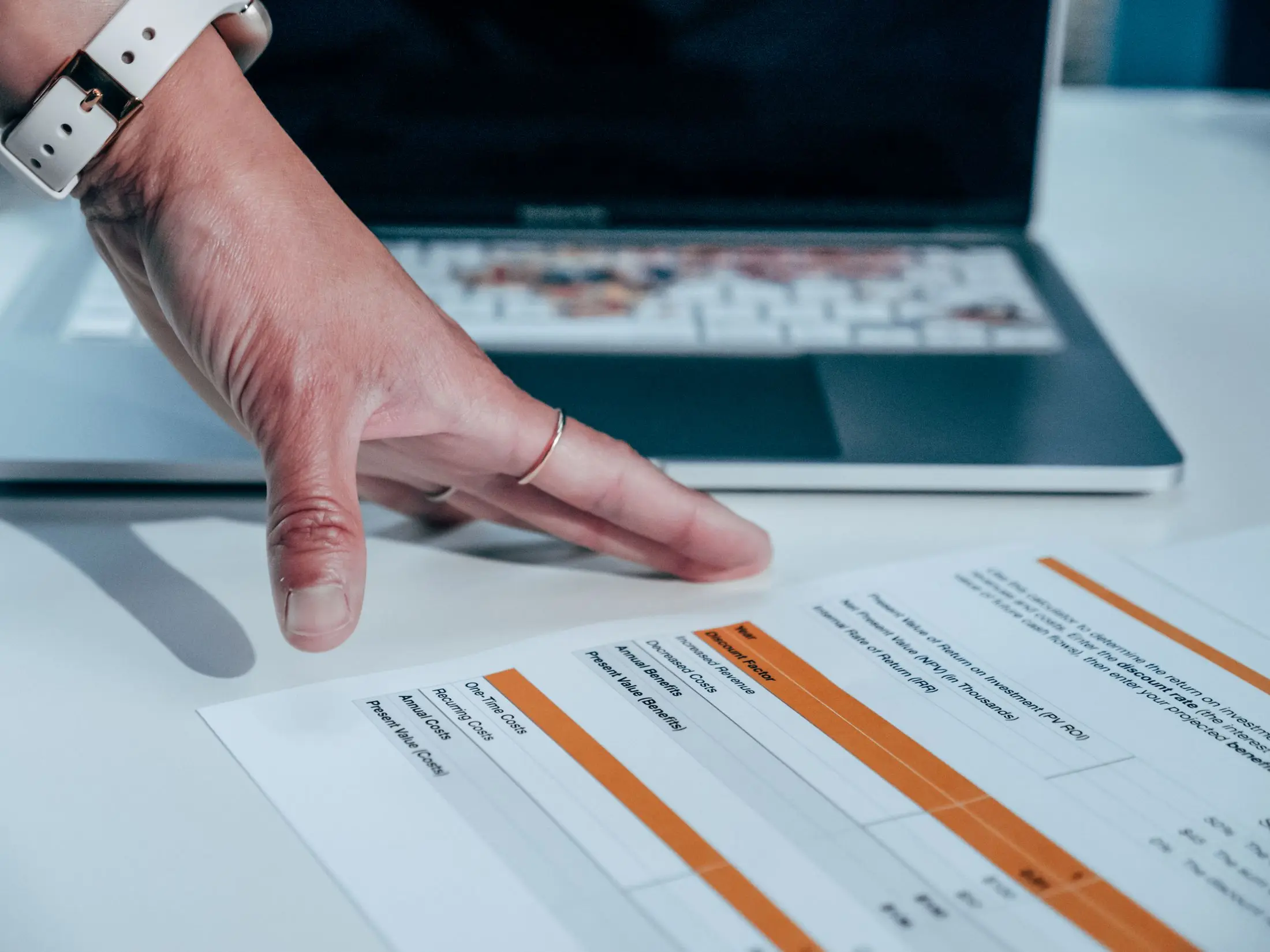 A professional reviewing a printed plan beside a laptop