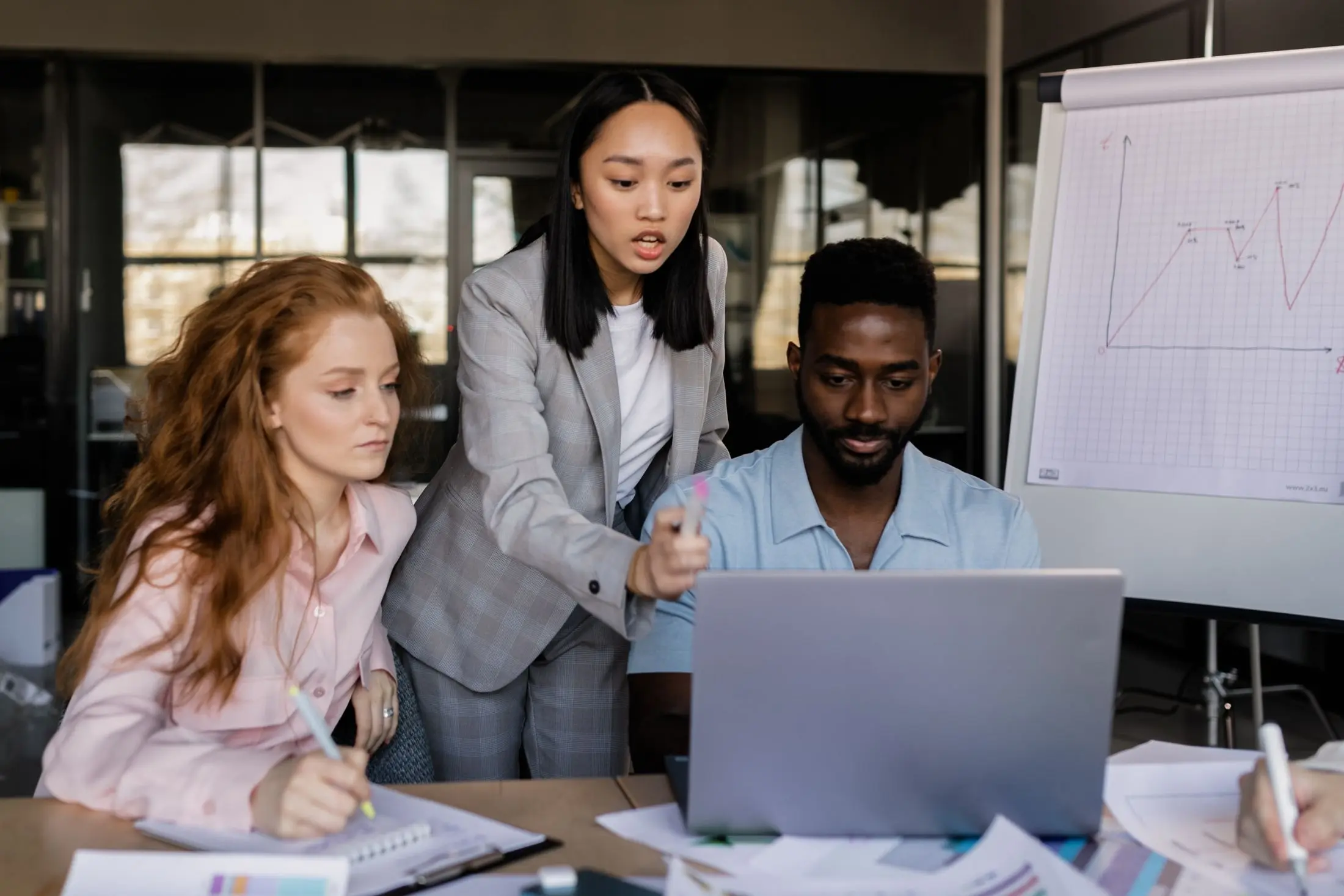 Three colleagues reviewing business information together in an office